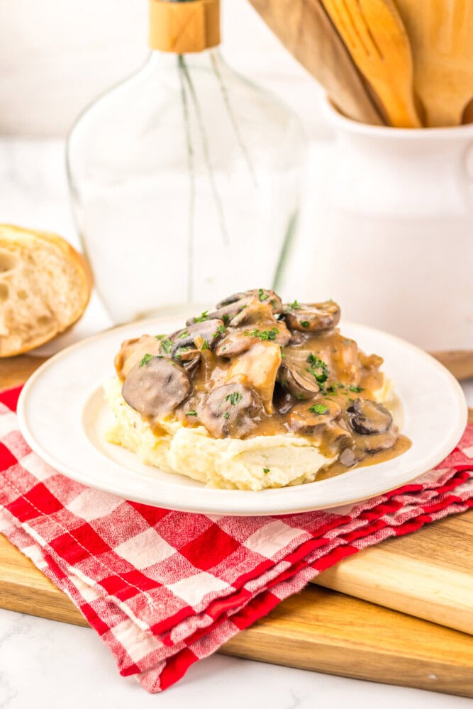 Slow cooker Salisbury chicken with mushroom gravy over mashed potatoes, garnished with parsley