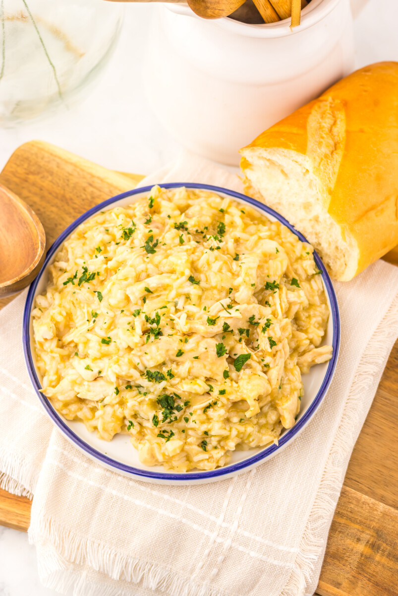 Slow cooker butter chicken and rice served in a blue-rimmed bowl with fresh parsley garnish and crusty bread