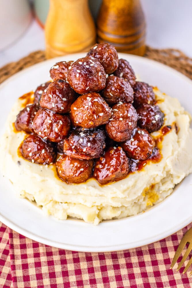 Slow cooker sticky sesame meatballs with sesame seeds on creamy mashed potatoes