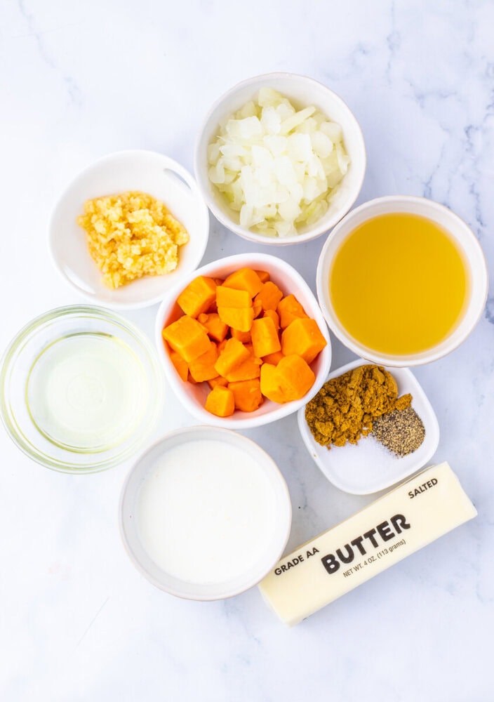 Creamy sweet potato soup ingredients prepped and arranged in bowls including sweet potatoes, onions, corn, broth, cream, butter and spices