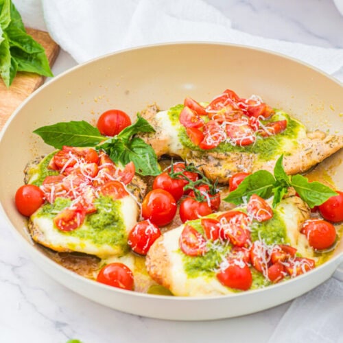 Chicken Margherita with melted mozzarella, fresh tomatoes, basil and pesto in a skillet
