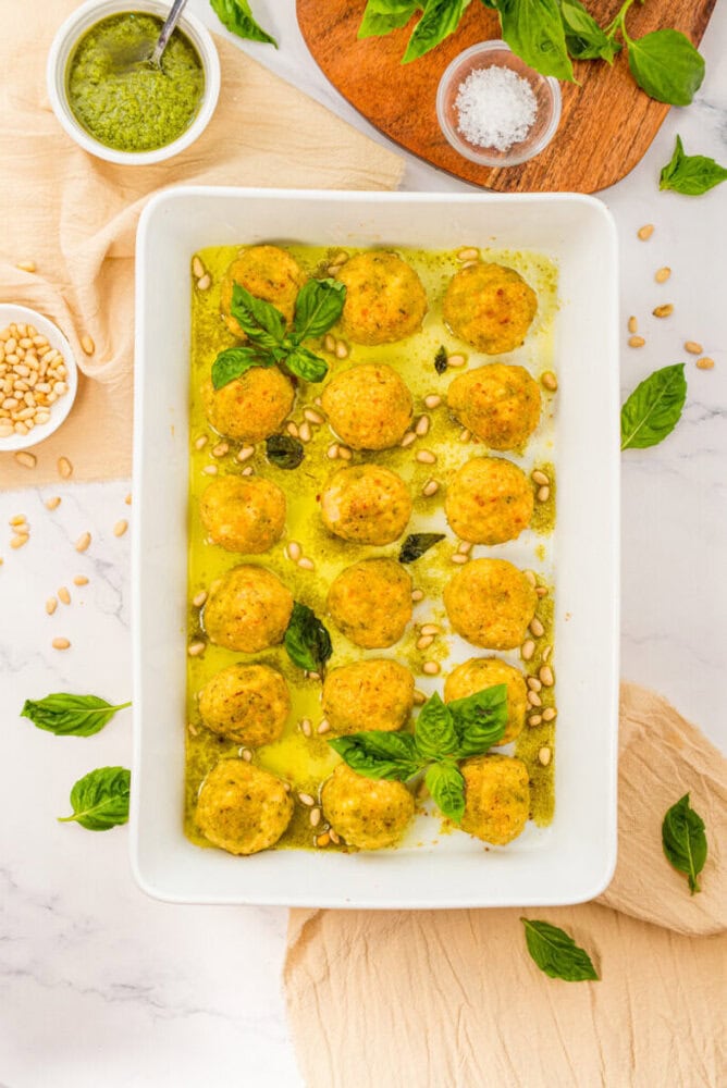 Chicken pesto meatballs in pesto sauce garnished with pine nuts and fresh basil
