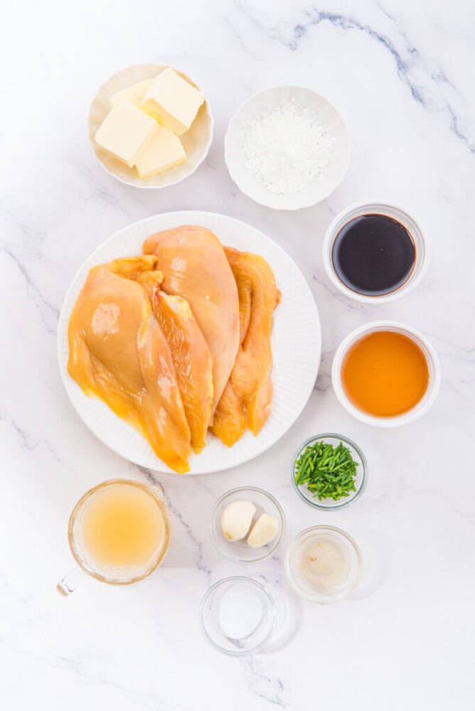 Honey butter chicken ingredients arranged overhead including cooked chicken, butter, flour, soy sauce, honey, garlic, and seasonings