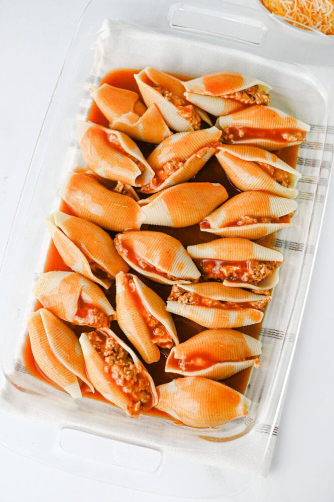 Cheesy taco stuffed shells in a white container, cooked and ready to serve