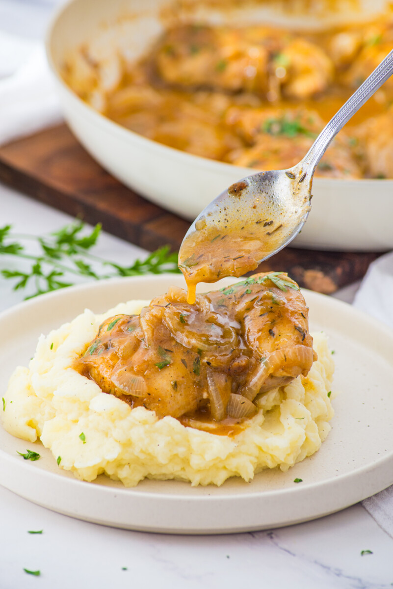 Smothered chicken with caramelized onions and gravy served over creamy mashed potatoes