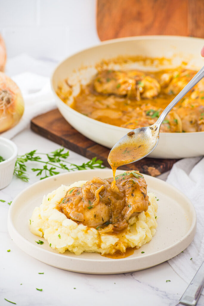 Smothered chicken with caramelized onions and gravy sauce served over creamy mashed potatoes