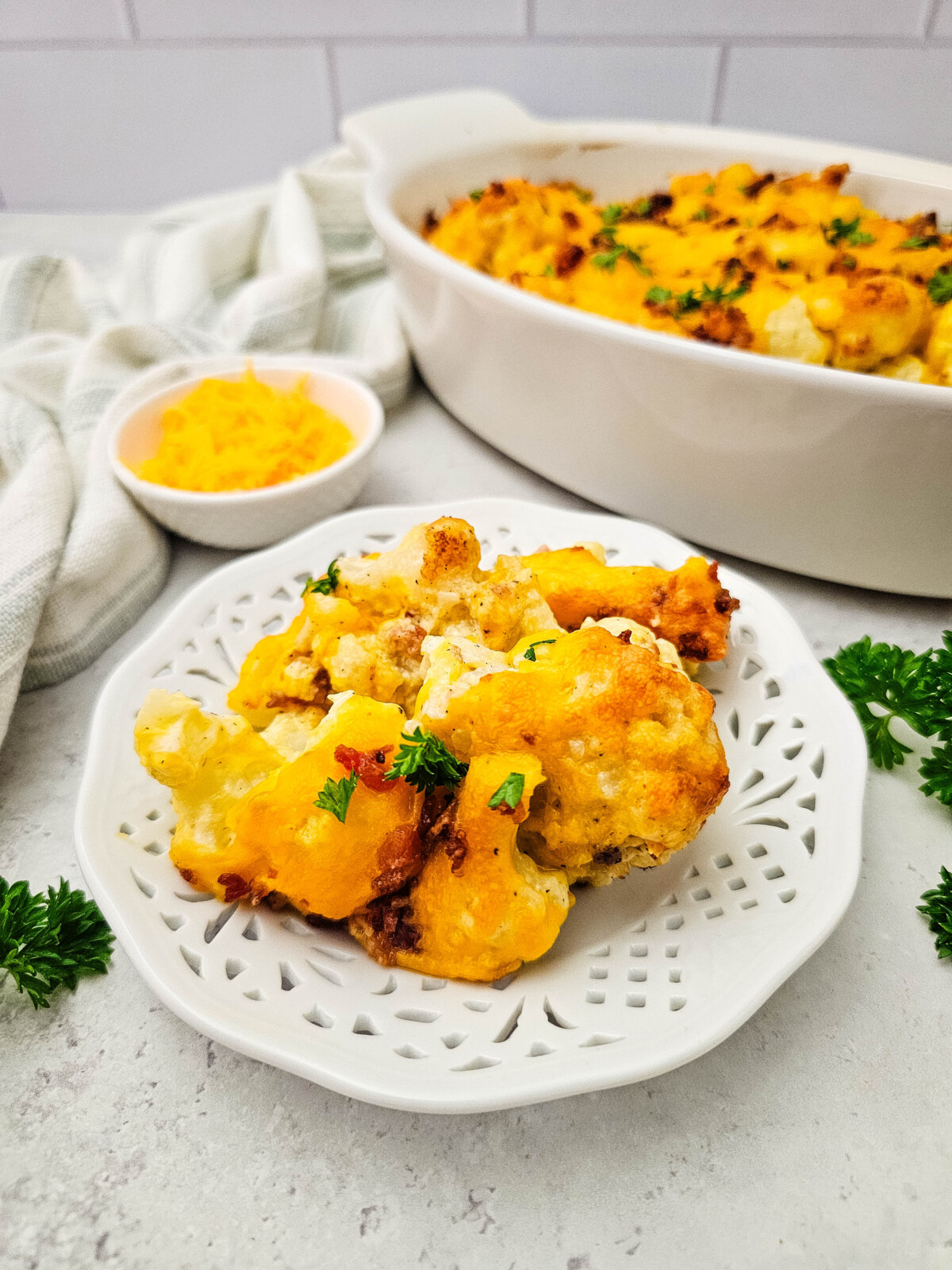 Baked cauliflower casserole with cheese topping served on white plate with fresh parsley garnish