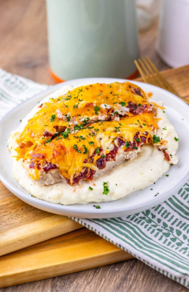 Cranberry Cream Cheese Chicken Bake with melted cheddar and bacon on mashed potatoes