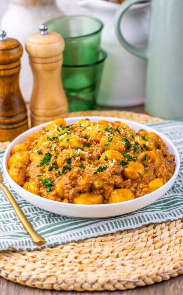 One Pan Gnocchi Shepherd's Pie with ground meat and golden potato cubes garnished with fresh parsley in a white bowl