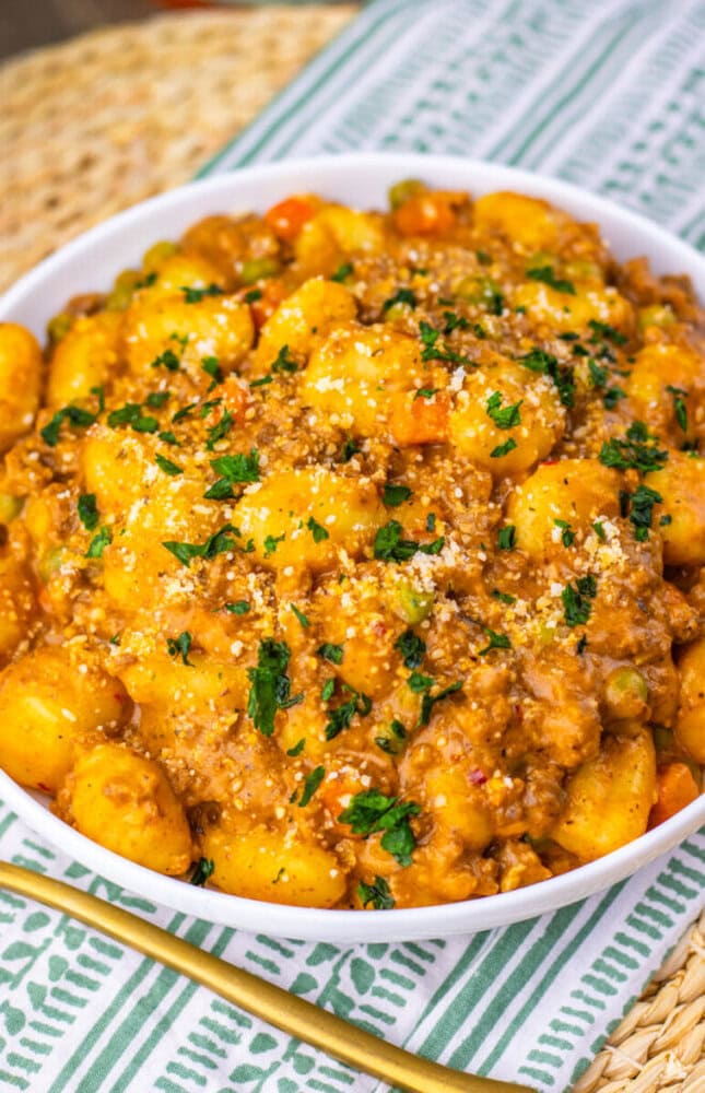 One pan gnocchi shepherd's pie with golden potato gnocchi, seasoned ground meat, and fresh parsley garnish in white bowl