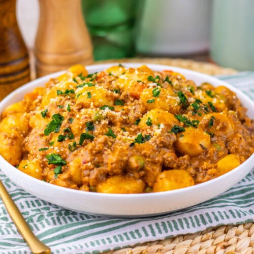 One Pan Gnocchi Shepherd's Pie with melted cheese and parsley garnish plated in white bowl