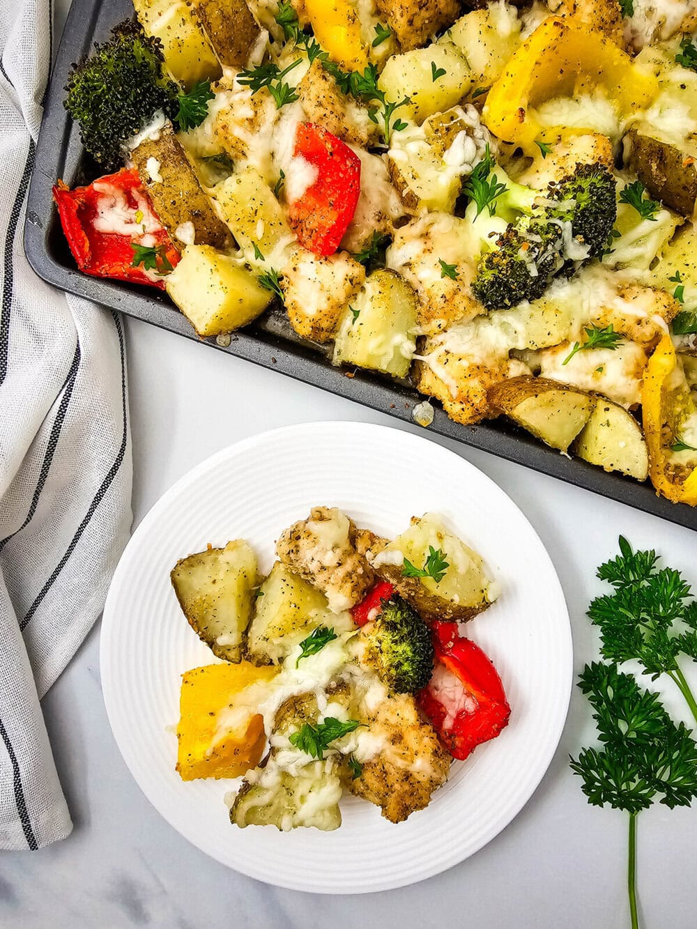 Sheet pan mozzarella chicken with roasted vegetables and melted cheese, plated and ready to serve
