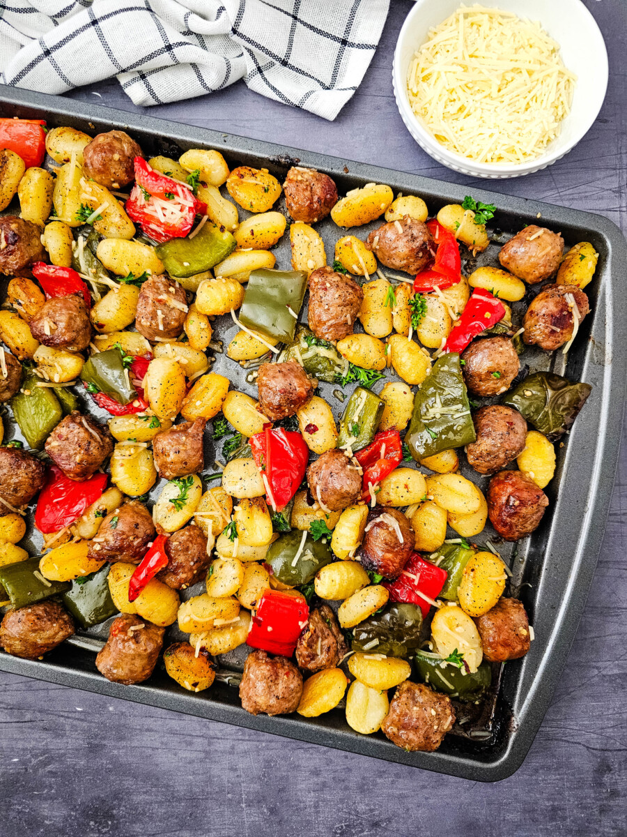 Sheet pan sausage and gnocchi with roasted peppers and parsley garnish