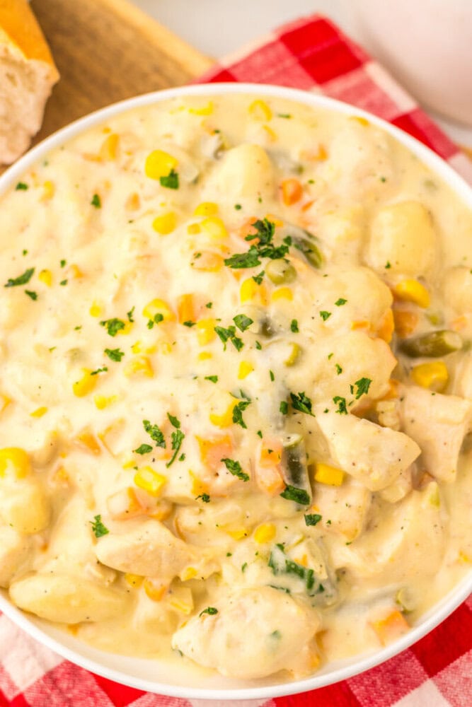 Slow cooker chicken pot pie gnocchi in creamy sauce with corn and vegetables garnish