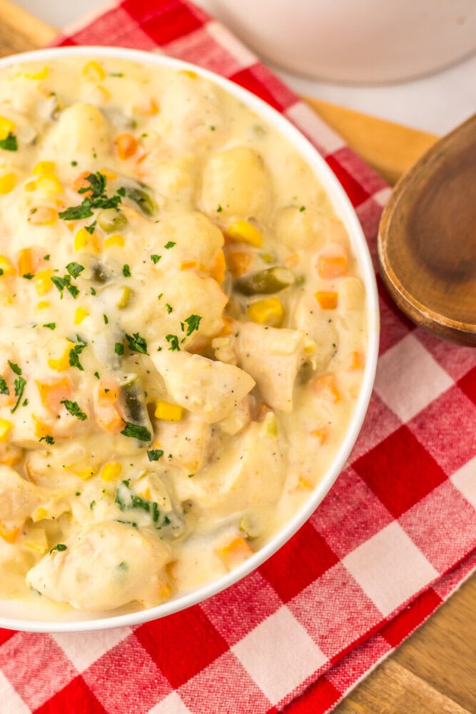 Slow cooker chicken pot pie gnocchi in creamy sauce with vegetables and fresh parsley garnish