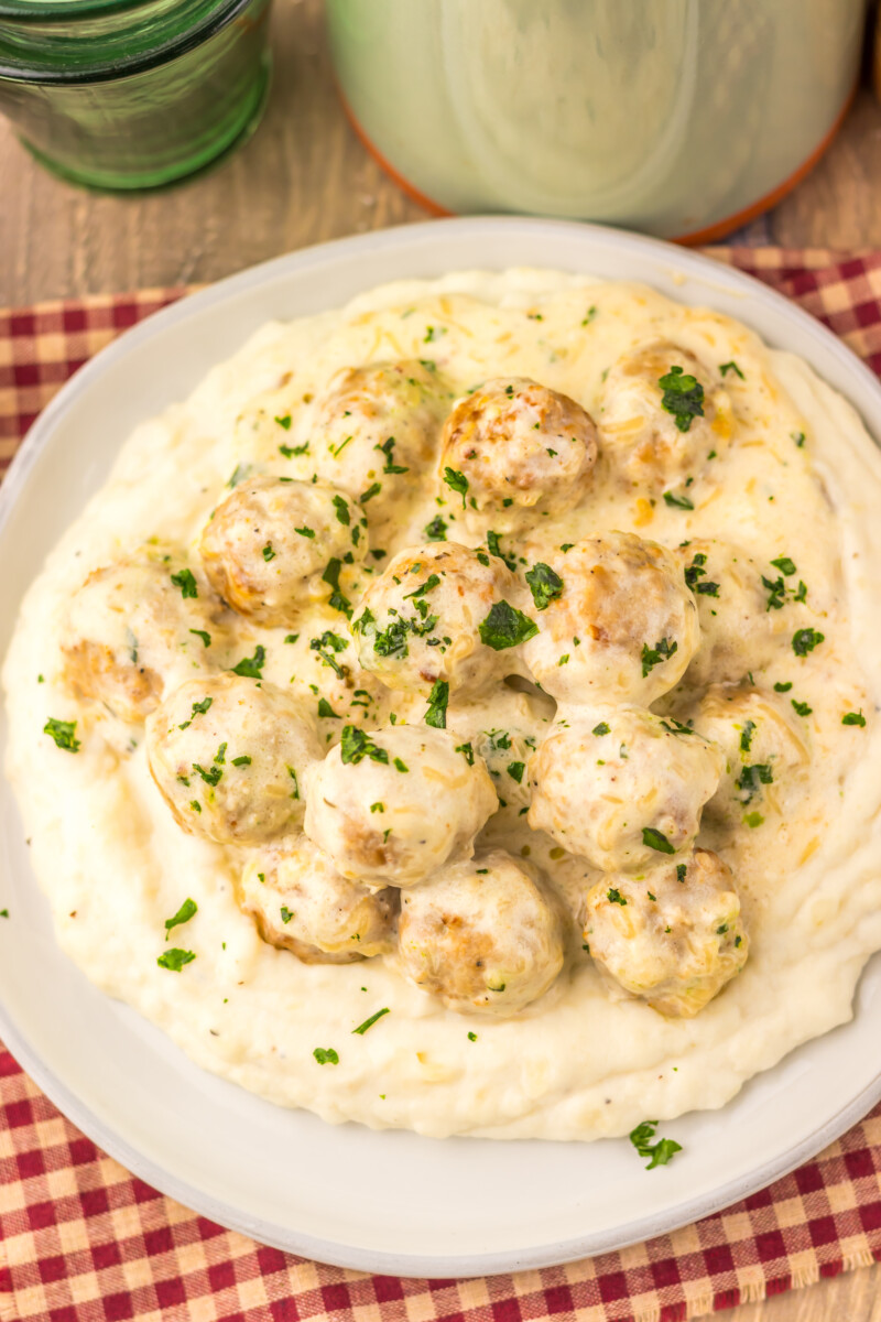 Slow cooker creamy alfredo meatballs served on a plate with sauce and parsley garnish