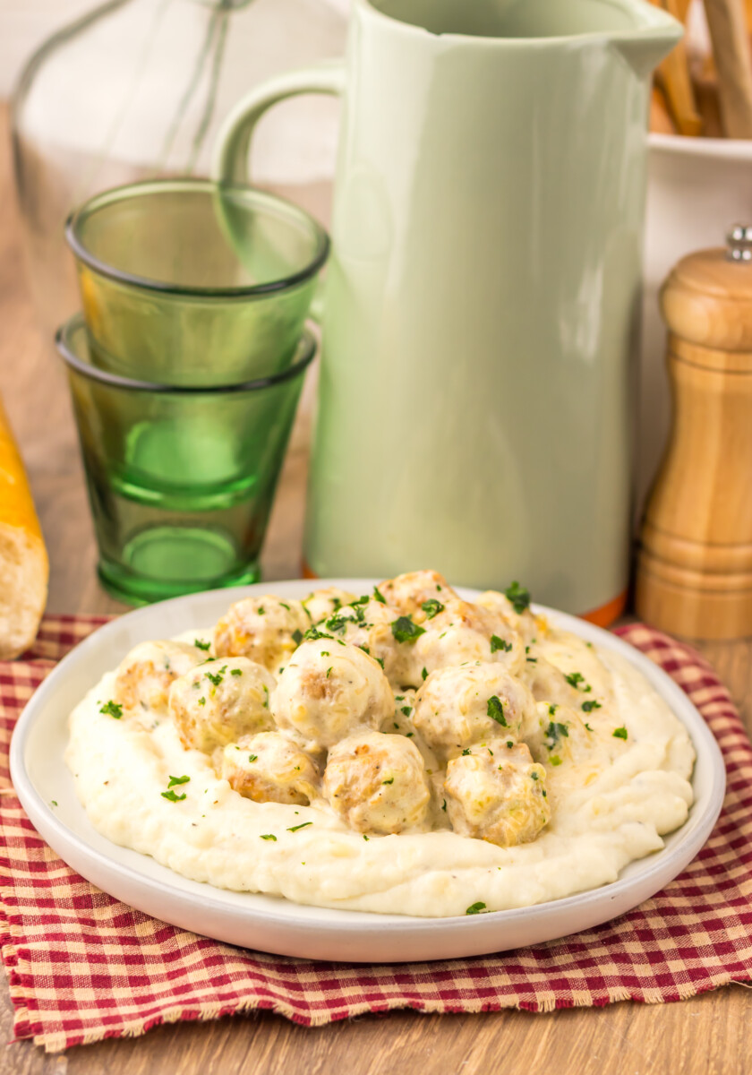 Slow cooker creamy alfredo meatballs served over mashed potatoes with parsley garnish