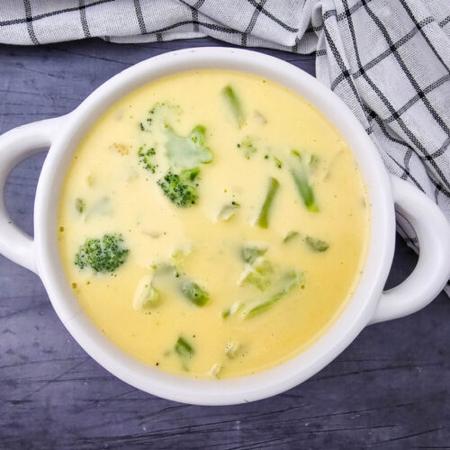Velveeta cheese broccoli soup in white bowl with broccoli garnish and pepper
