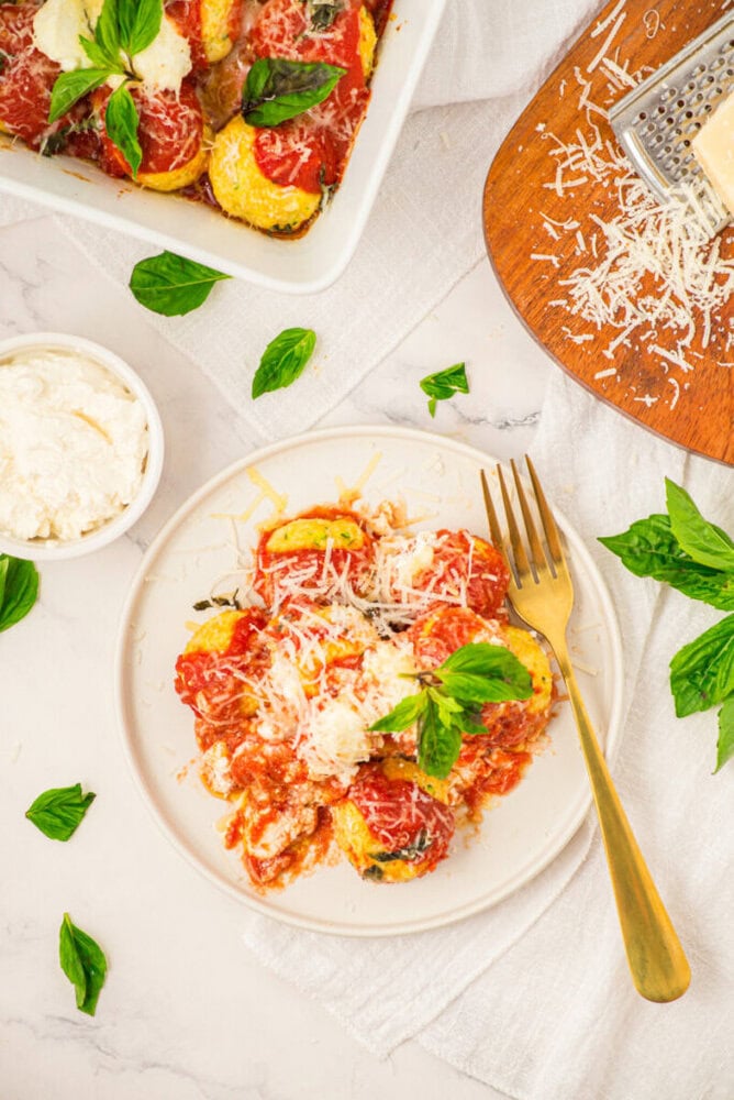 Chicken ricotta meatballs with tomato sauce, melted cheese and fresh basil on white plate