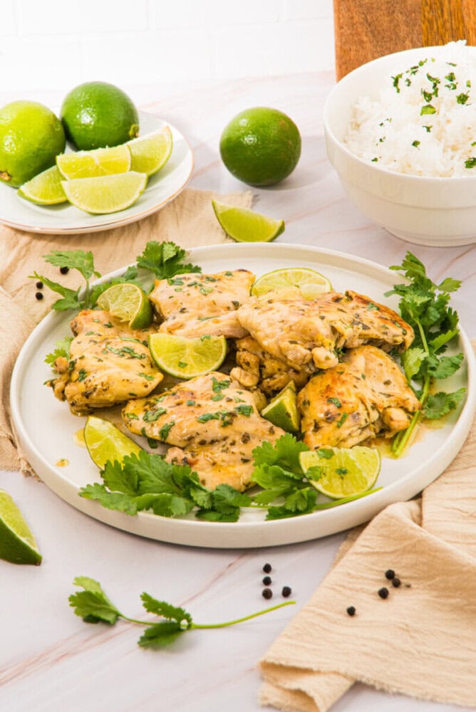 Cilantro lime chicken breasts plated with fresh herbs, lime garnish, and cilantro lime rice