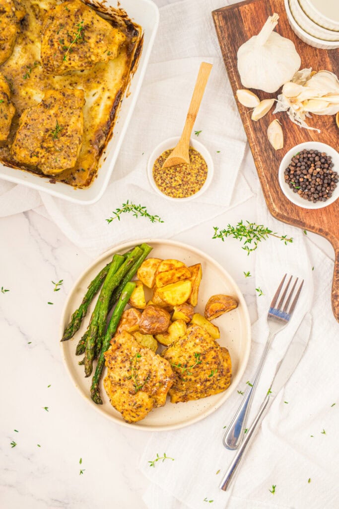 Plated mustard chicken thighs with roasted potatoes and asparagus, overhead shot