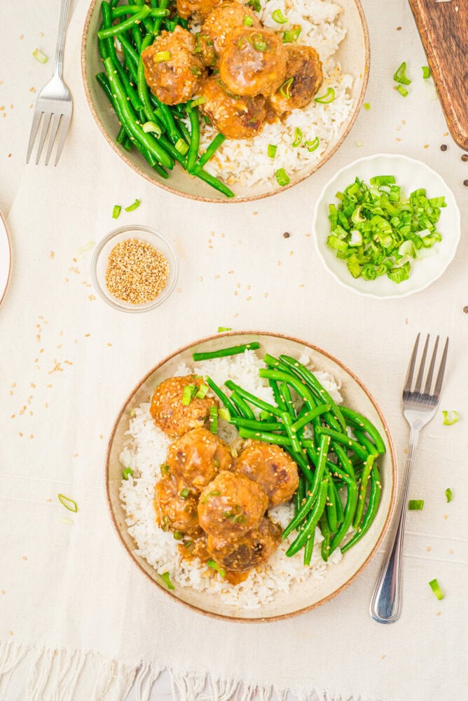 Pork meatballs with soy butter sauce served over rice with green beans and sesame seeds