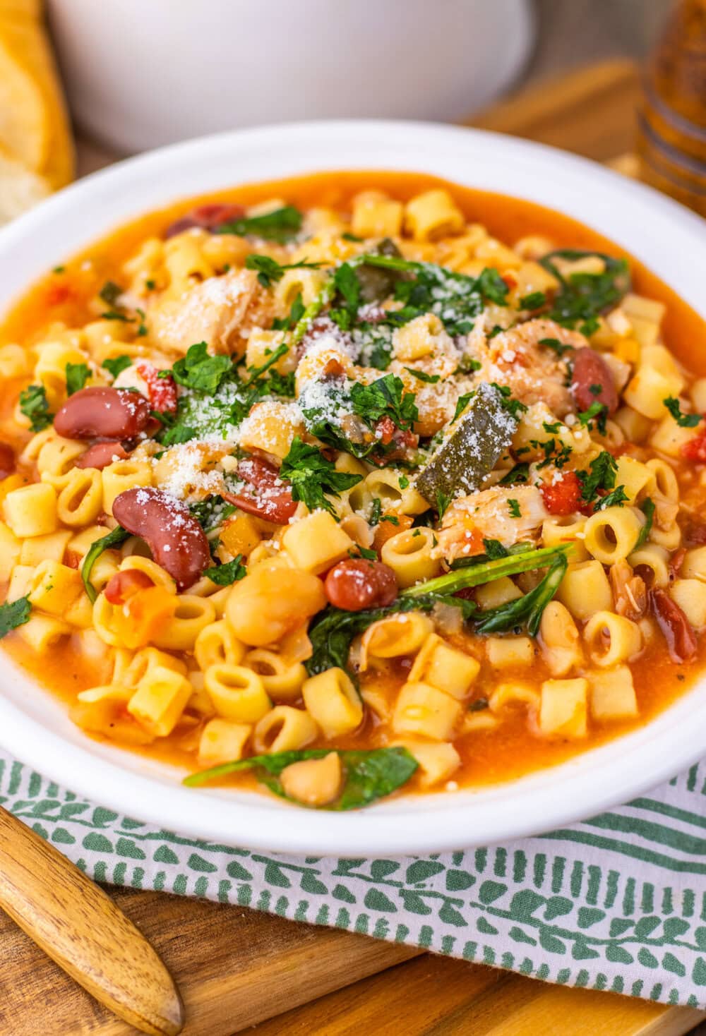Slow cooker chicken minestrone soup with ditalini pasta, beans, and fresh herbs in white bowl