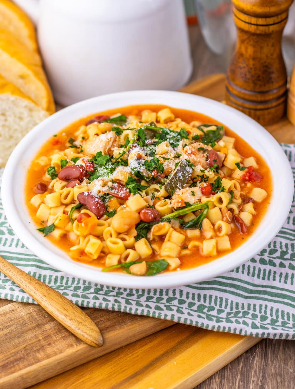 Slow cooker chicken minestrone soup served in white bowl with pasta, vegetables, and fresh herbs garnish
