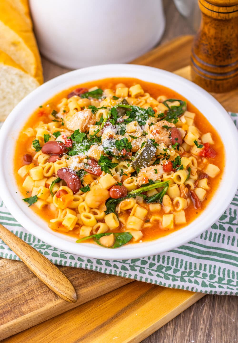 Slow cooker chicken minestrone soup in white bowl with pasta, beans, and fresh parsley garnish