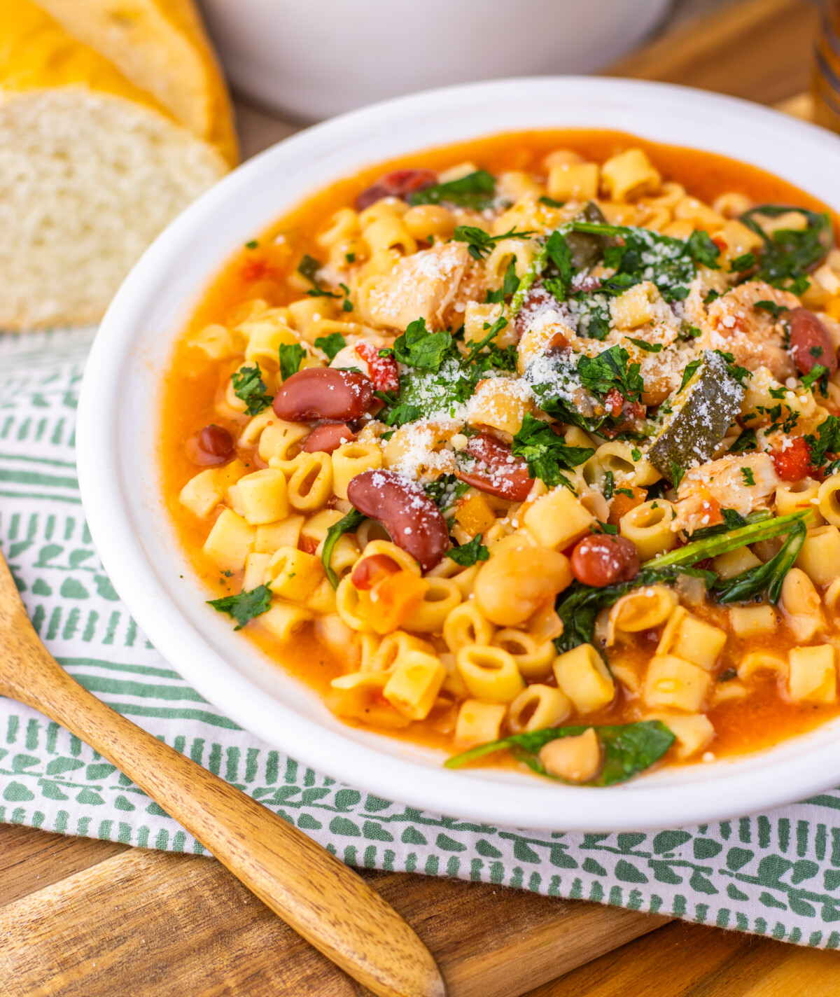 Slow cooker chicken minestrone soup in white bowl with pasta, beans, and fresh parsley garnish
