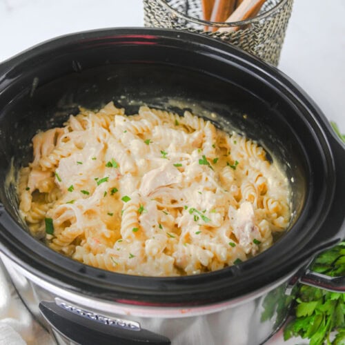 Creamy crockpot ranch chicken pasta with fresh parsley garnish in slow cooker