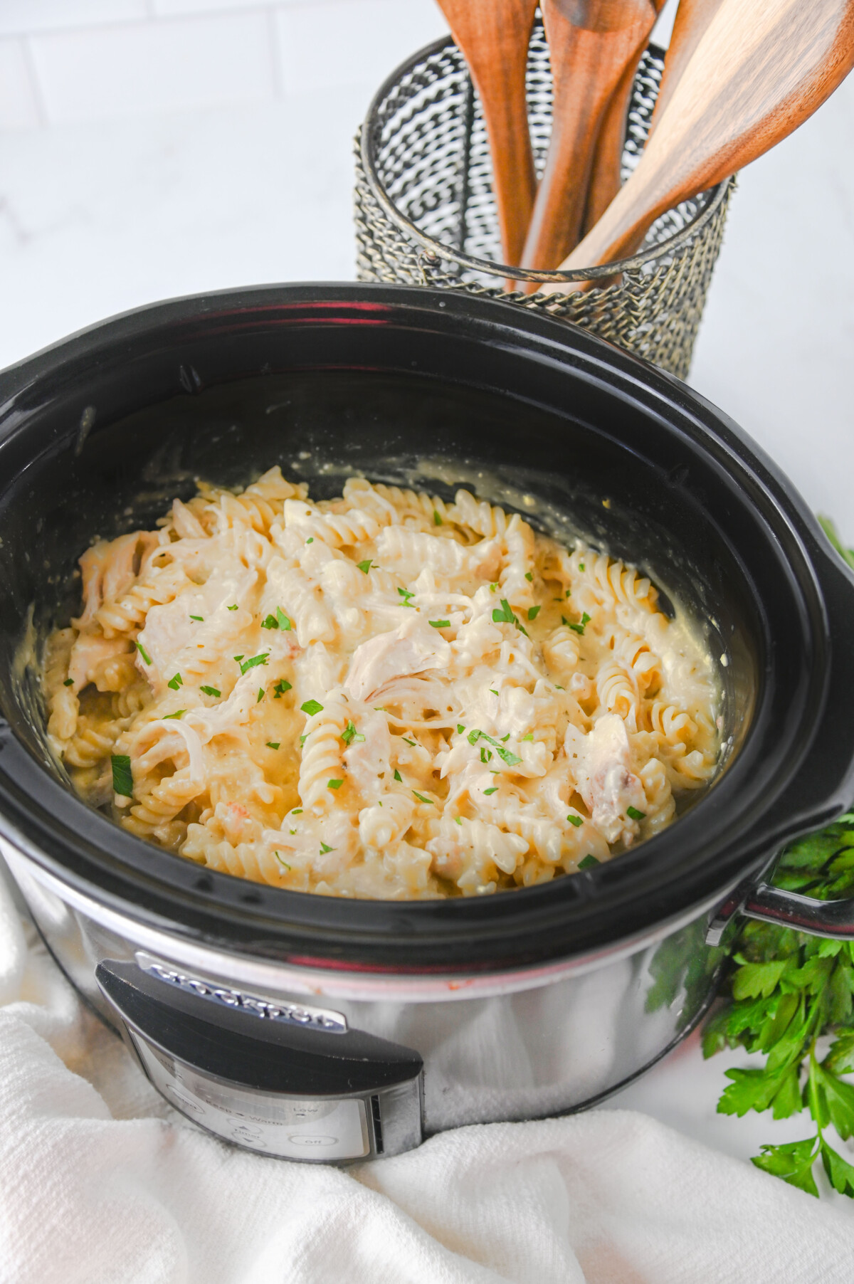 Creamy crockpot ranch chicken pasta with fresh parsley garnish in slow cooker