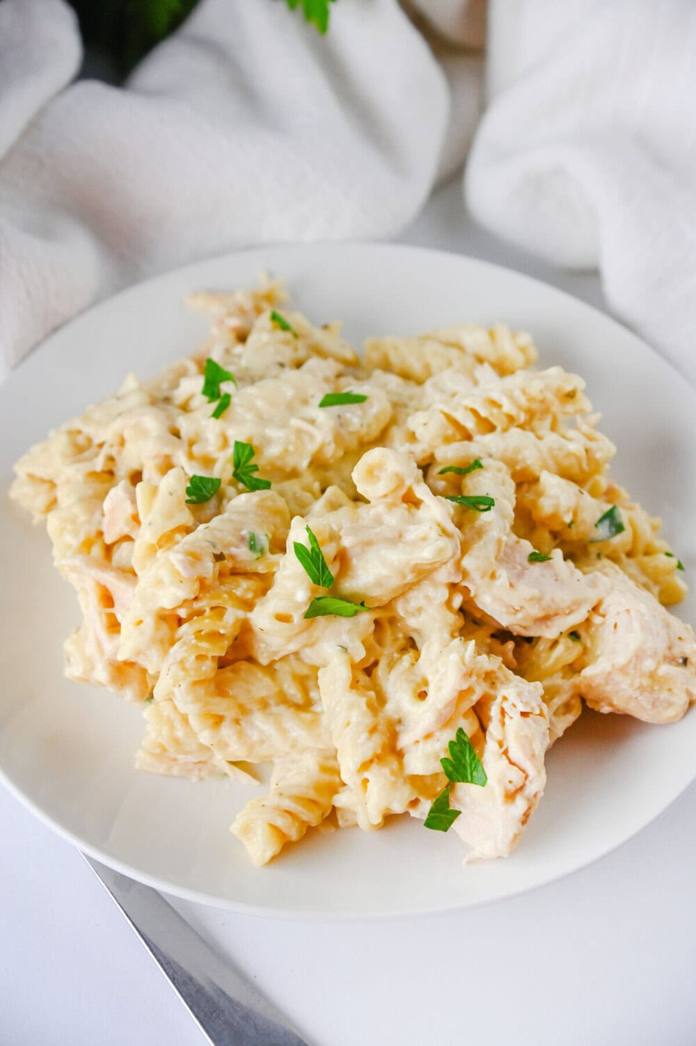 Crockpot ranch chicken pasta with creamy sauce and parsley garnish on white plate