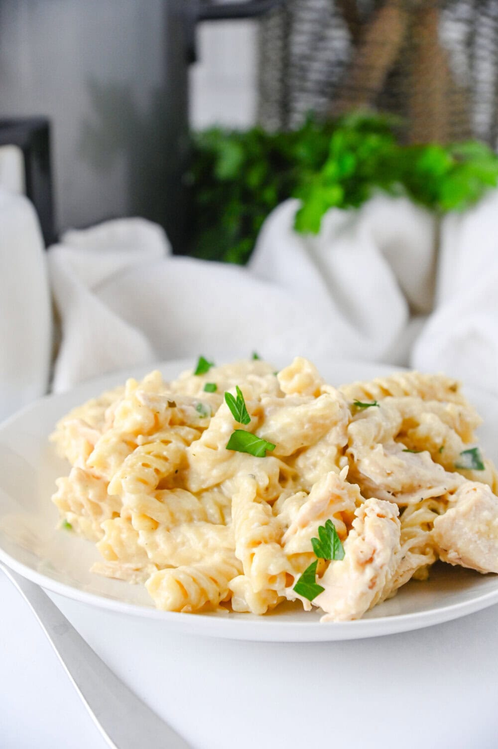 Crockpot ranch chicken pasta with rotini noodles and parsley garnish on white plate