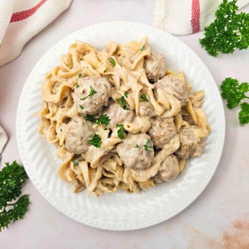 Crockpot Swedish meatballs with egg noodles and creamy sauce garnished with parsley