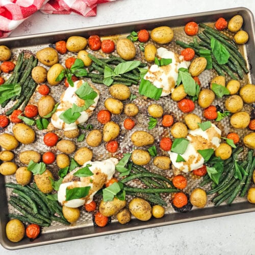 Sheet Pan Chicken Caprese with roasted potatoes, tomatoes, green beans and melted mozzarella garnished with fresh basil
