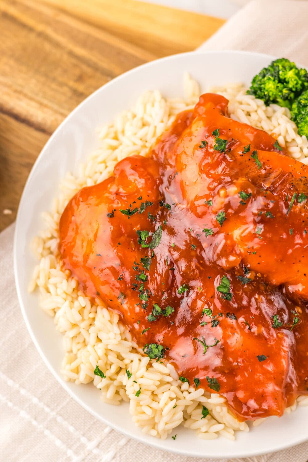Slow cooker catalina chicken with glossy red glaze served over rice pilaf with broccoli