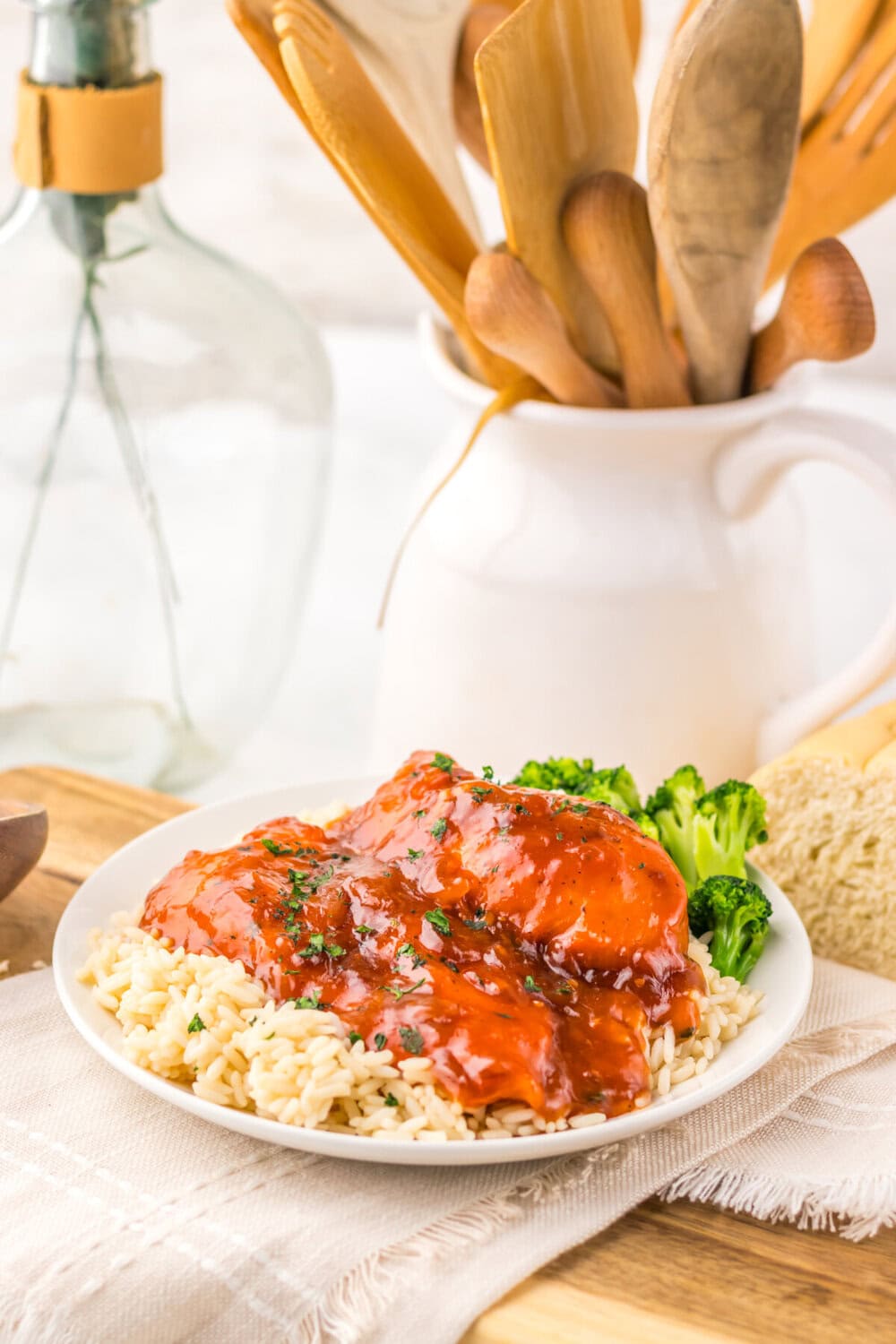 Slow cooker Catalina chicken glazed with red sauce served over pasta with broccoli on white plate