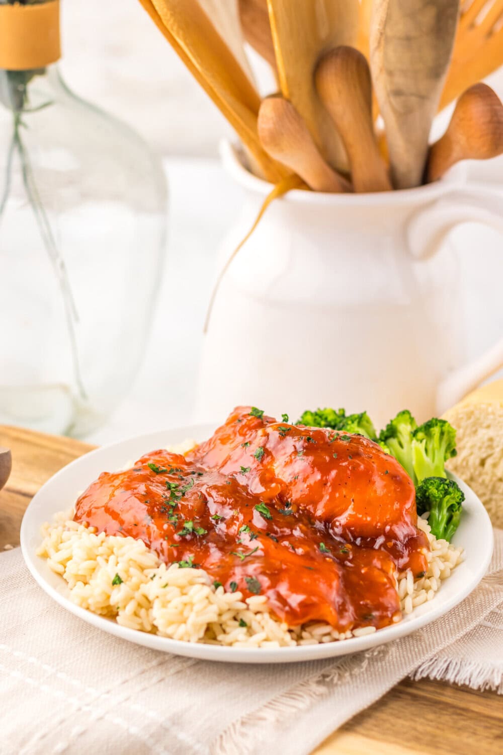 Slow cooker Catalina chicken with glossy sauce served over pasta and broccoli on white plate