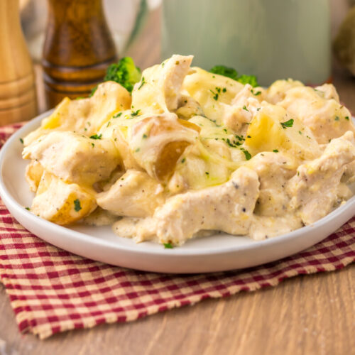 Slow cooker cheesy caesar chicken and potatoes plated and garnished with parsley