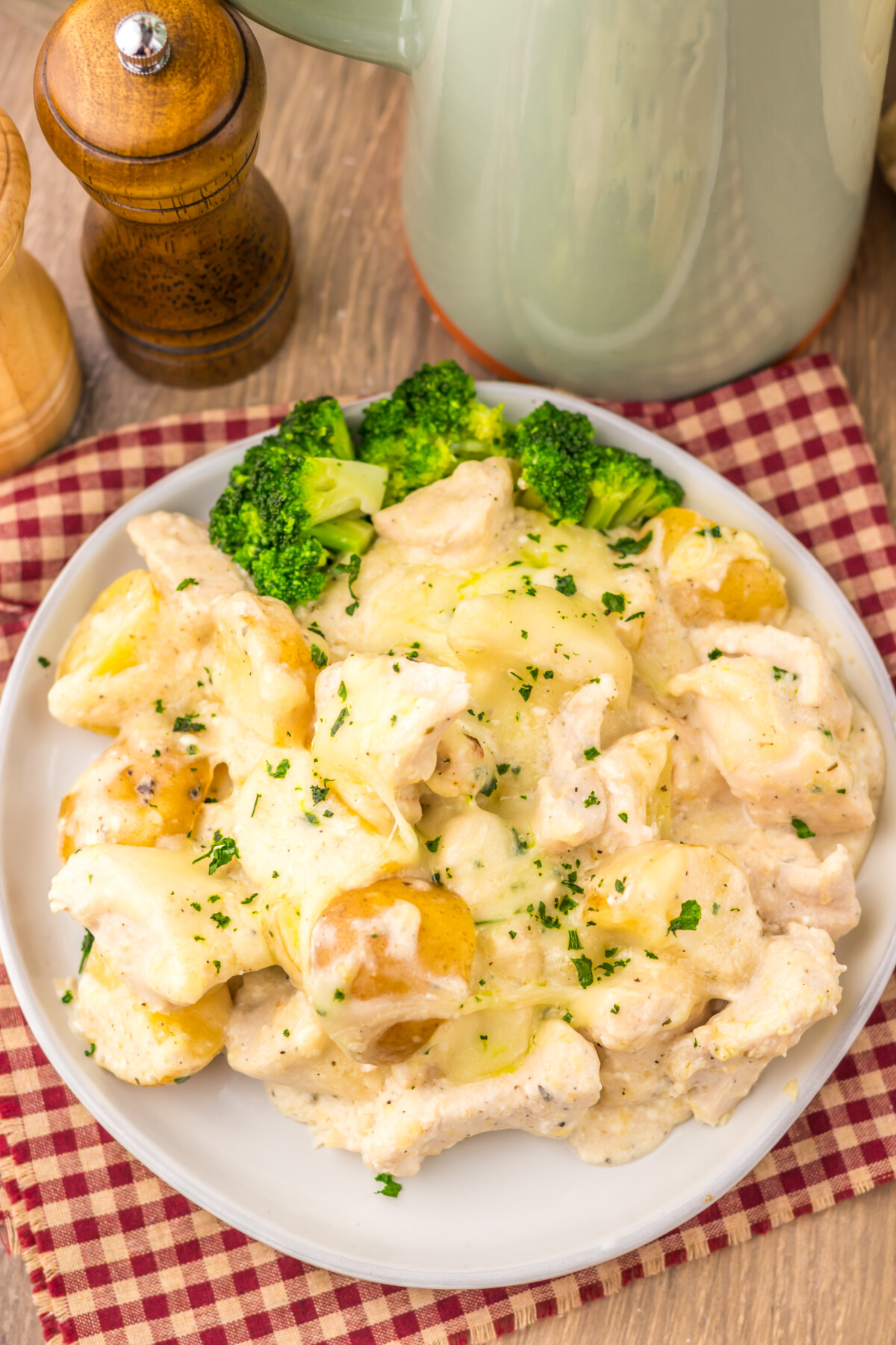 Slow cooker cheesy Caesar chicken and potatoes plated with broccoli garnish