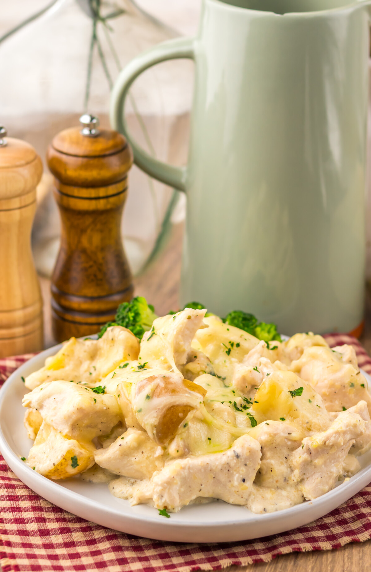 Slow cooker cheesy Caesar chicken and potatoes plated on white dish with parsley garnish