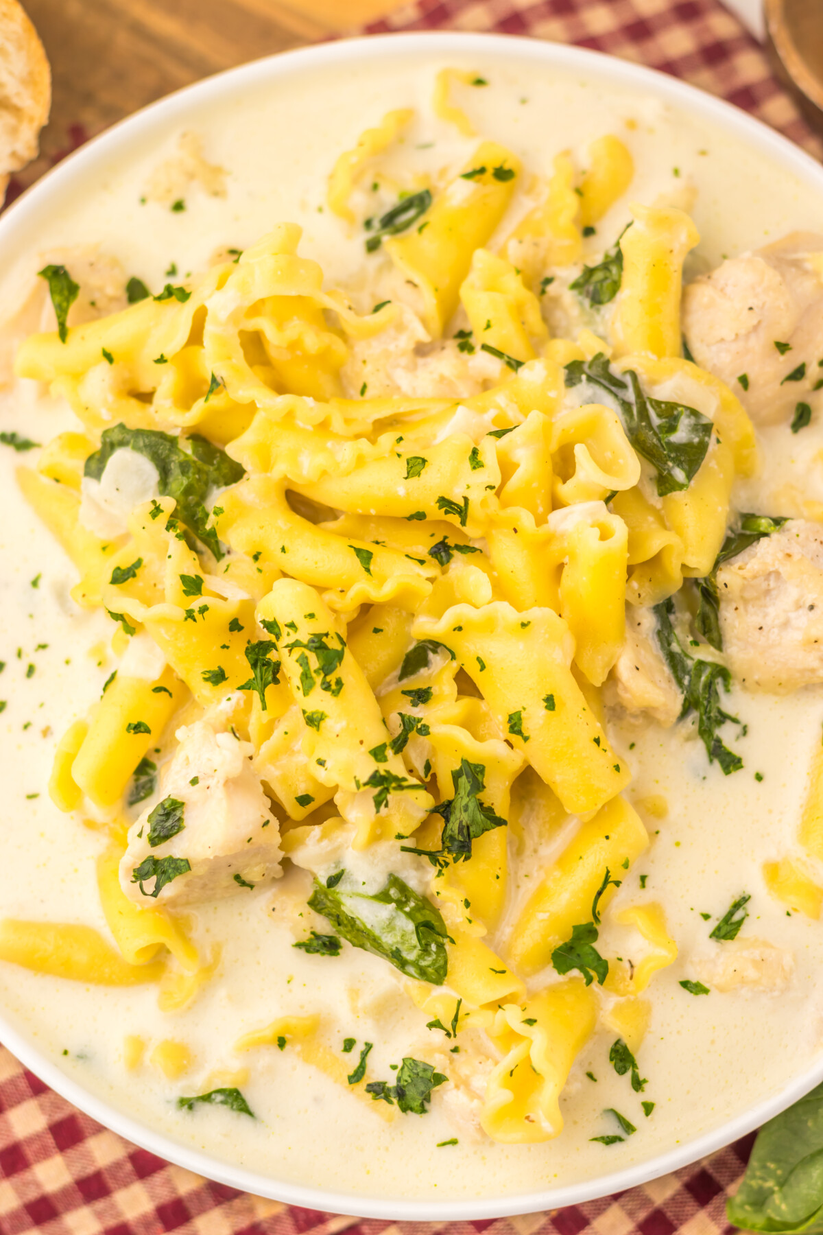 Slow Cooker Chicken Alfredo Soup with egg noodles, chicken, and fresh basil garnish in creamy sauce