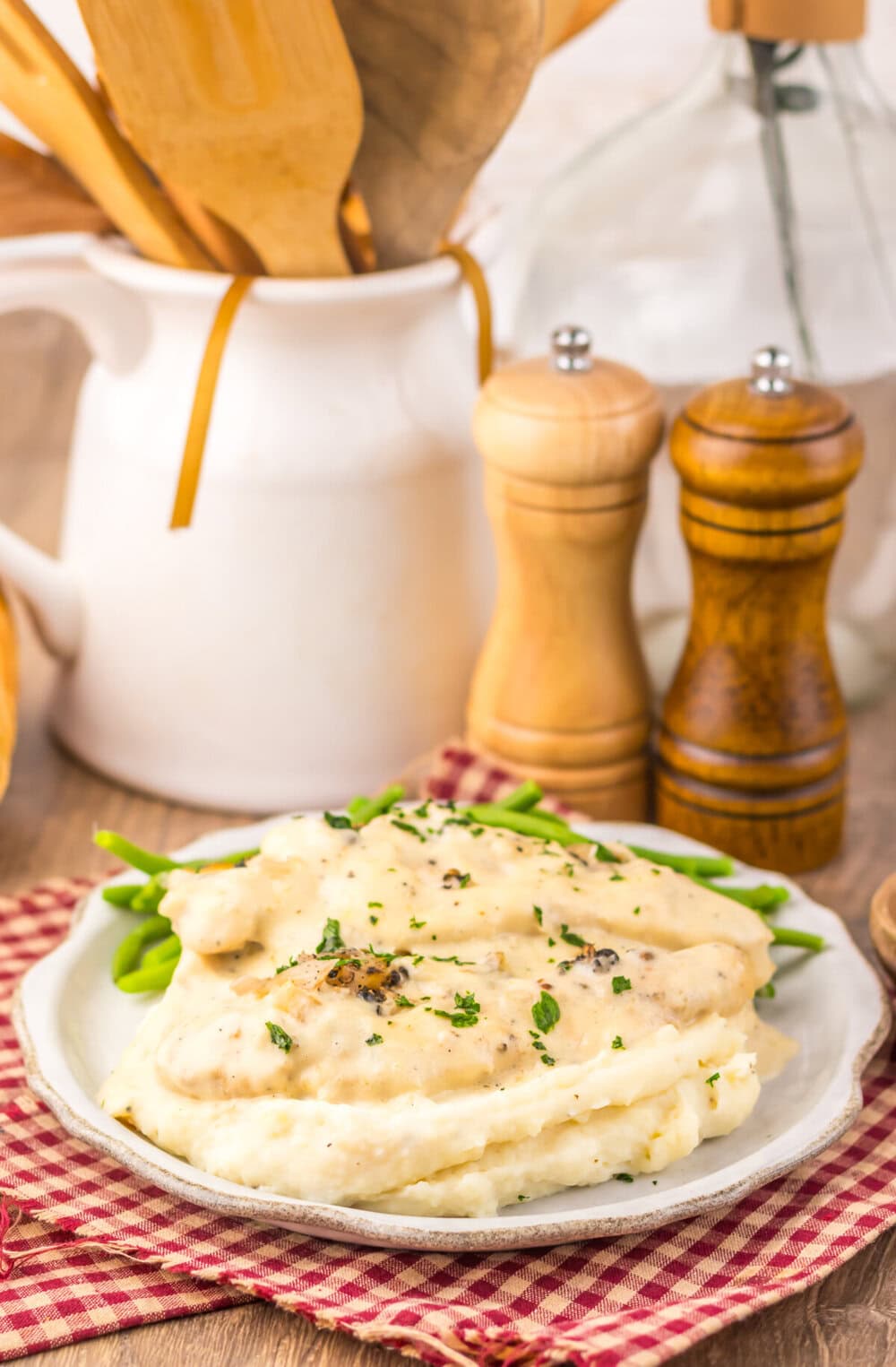 Slow cooker chicken au poivre plated with green beans and mashed potatoes, garnished with fresh herbs