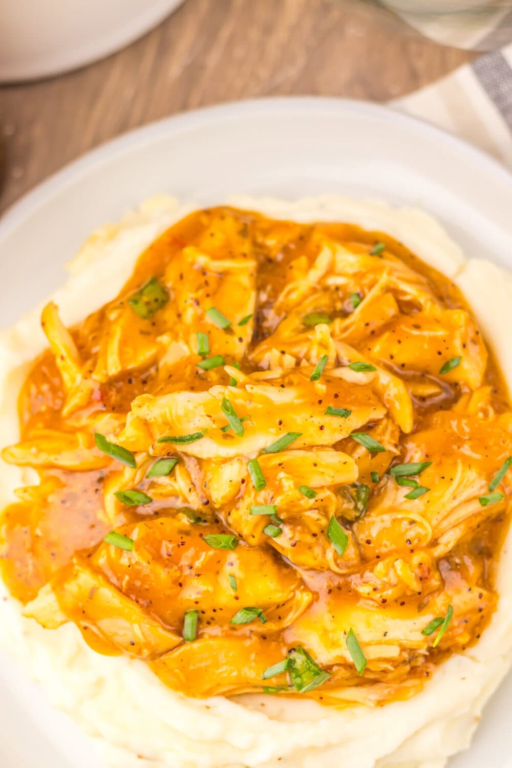 Slow cooker sweet onion teriyaki chicken served over mashed potatoes with green onion garnish