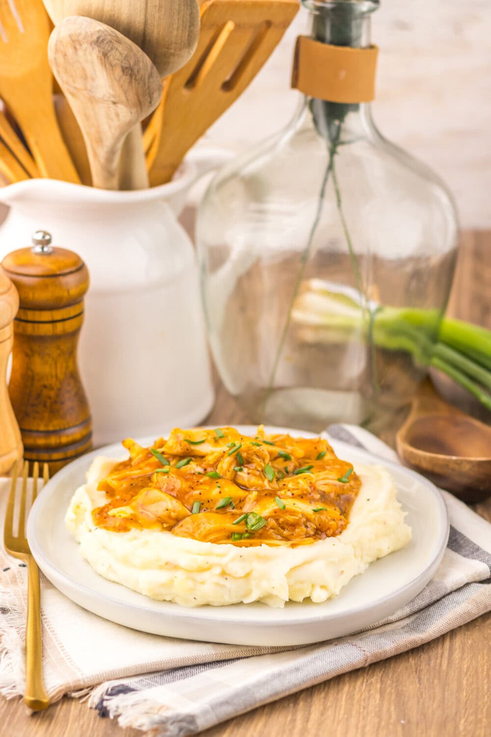 Slow cooker sweet onion teriyaki chicken over mashed potatoes garnished with green onions on a white plate