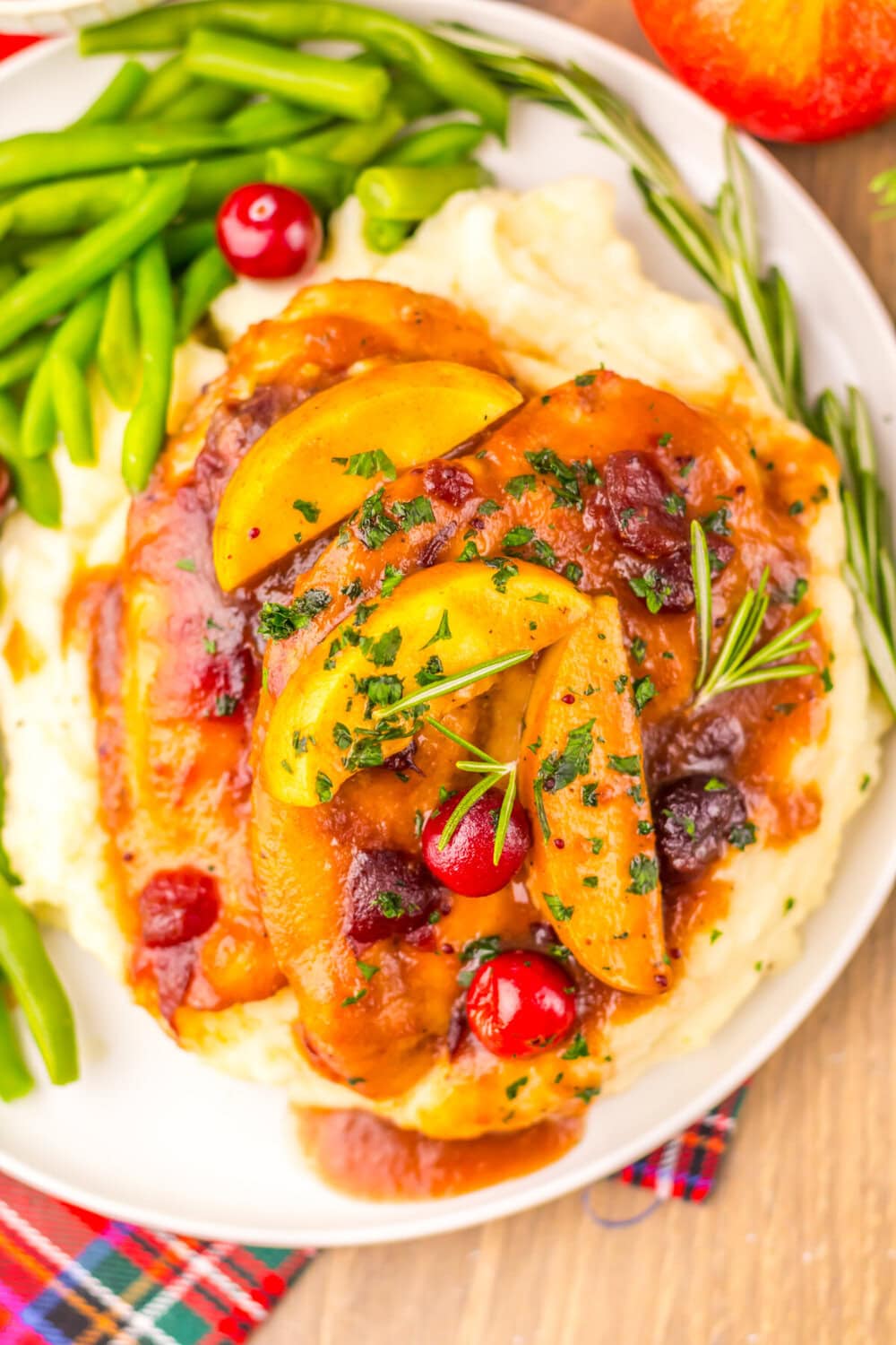 Slow cooker cranberry apple chicken with golden apples and fresh herbs served with mashed potatoes and green beans