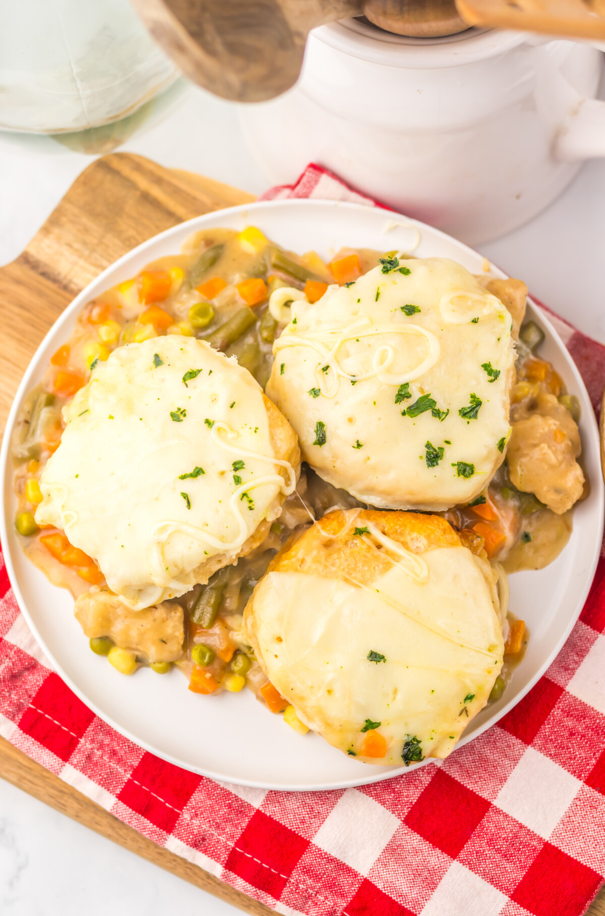 Slow cooker French onion chicken pot pie with melted cheese and fresh herbs on white plate